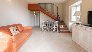 Un salon avec un canapé, une table à manger et des chaises, un escalier et un meuble.
