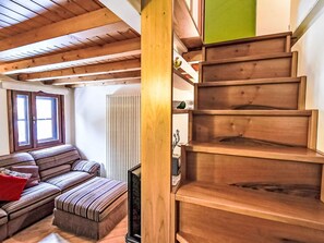 A wooden staircase with a green panel on the right, a striped sofa, and a radiator in the background. - Nice apartment for 4 people with WIFI and TV (Madesimo)