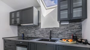 A modern kitchen with dark cabinetry, a stone backsplash, a skylight, and a coffee maker on the counter. - Wonderful  villa for 8 people with A/C, WIFI, TV, terrace and panoramic view (Cecina)