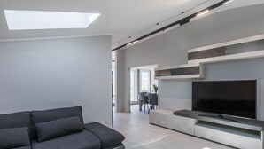 A modern living room with a grey sofa, a glass coffee table, and a flat-screen TV mounted on a white wall. - Wonderful  villa for 8 people with A/C, WIFI, TV, terrace and panoramic view (Cecina)