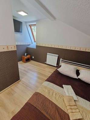 Quarto com cama, mesa de cabeceira, radiador e janela.