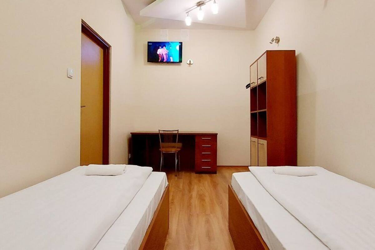 Une chambre avec deux lits simples, un bureau avec une chaise, une télévision et une armoire.