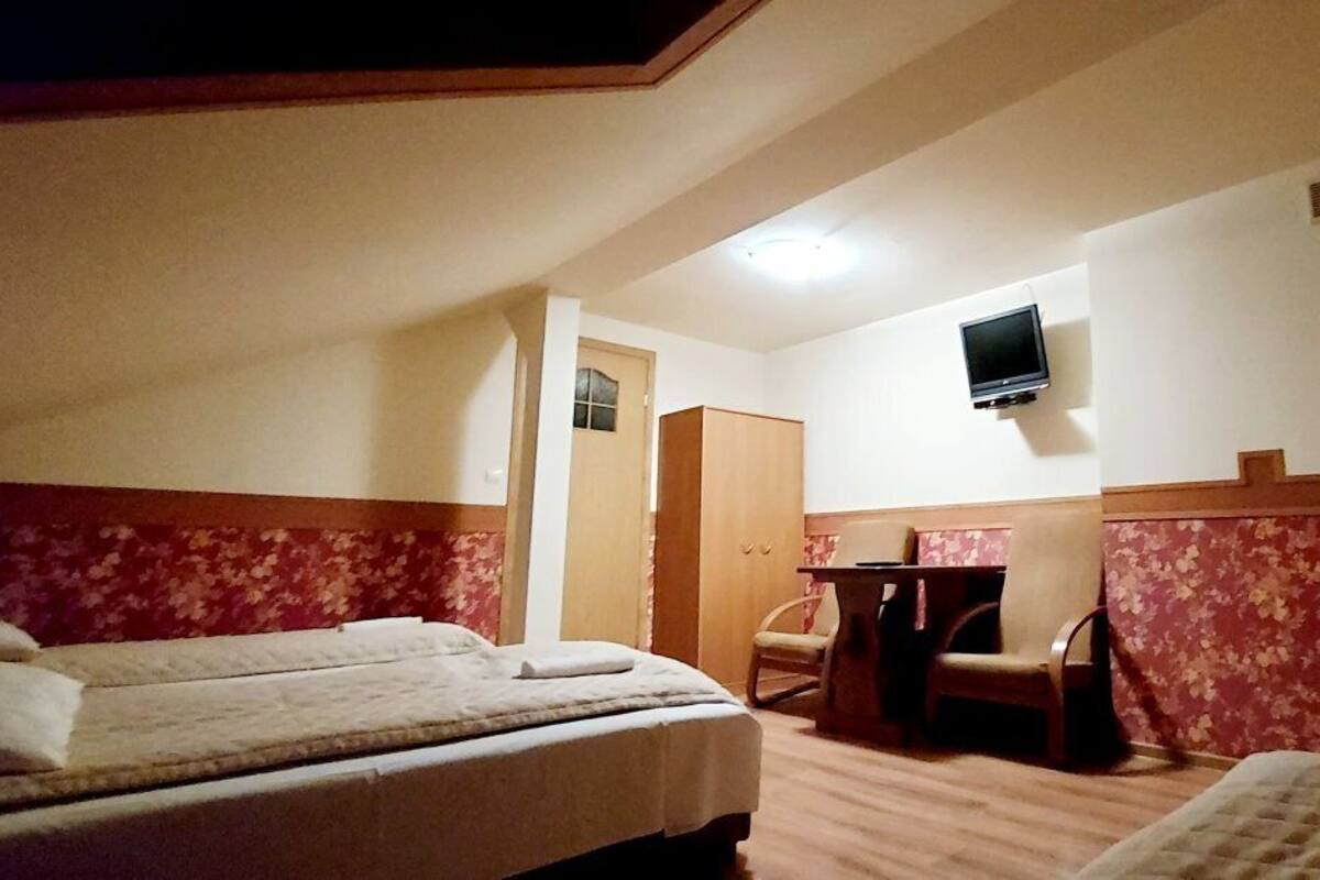 Une chambre d’hôtel avec deux lits, une petite table, une chaise et un téléviseur fixé au mur.