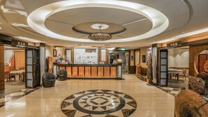 A hotel lobby with a central reception desk, seating areas, and a decorative circular floor pattern. - Sunrise Hot Spring Hotel (Taian)