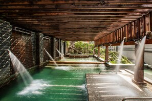 A spa area with a wooden ceiling, a stone wall, and a pool with water jets. - Sunrise Hot Spring Hotel (Taian)