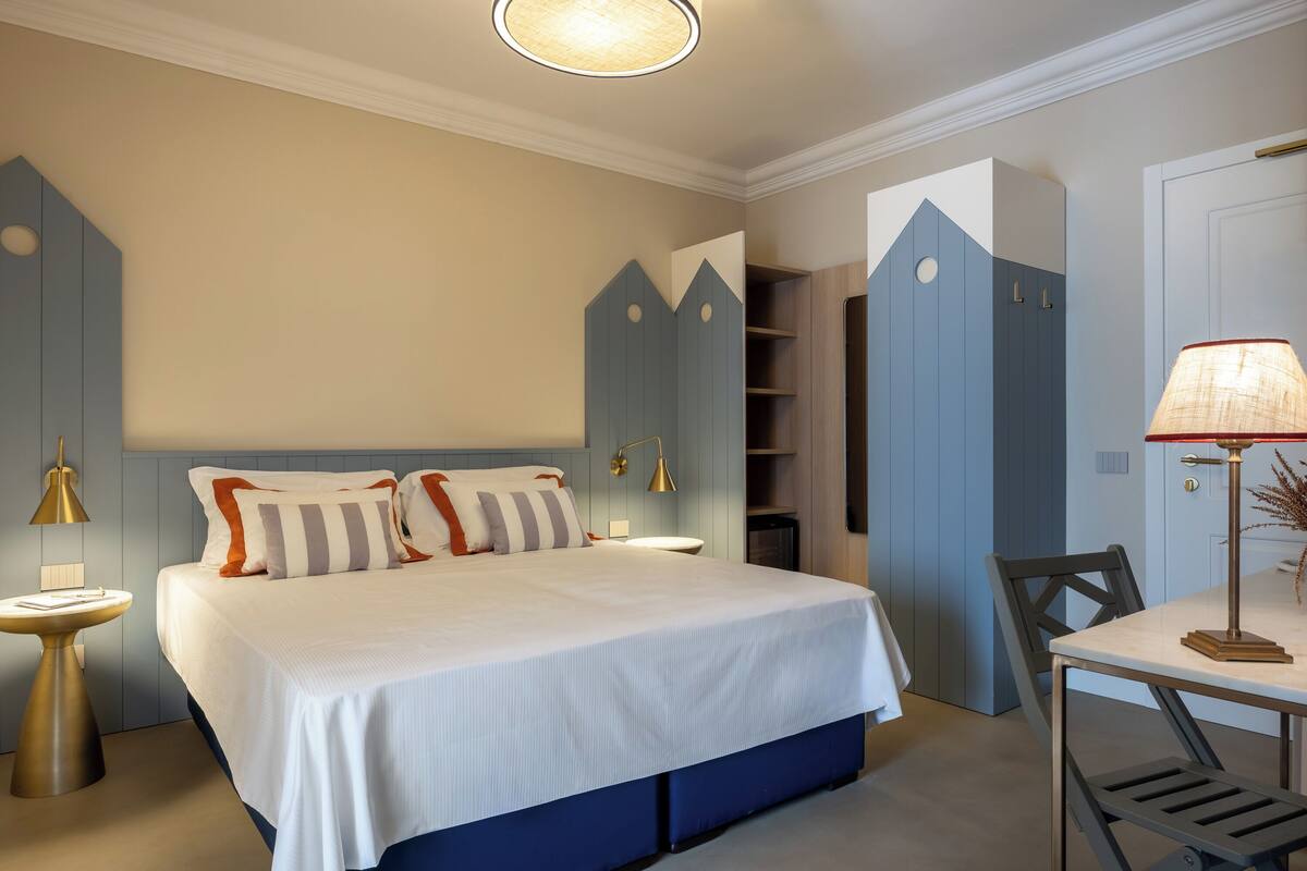 A bedroom with a large bed, bedside tables, a desk with a chair, and built-in wardrobes.