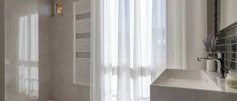 Un baño moderno con cabina de ducha de vidrio, inodoro, bañera y tocador con lavabo y espejo.
