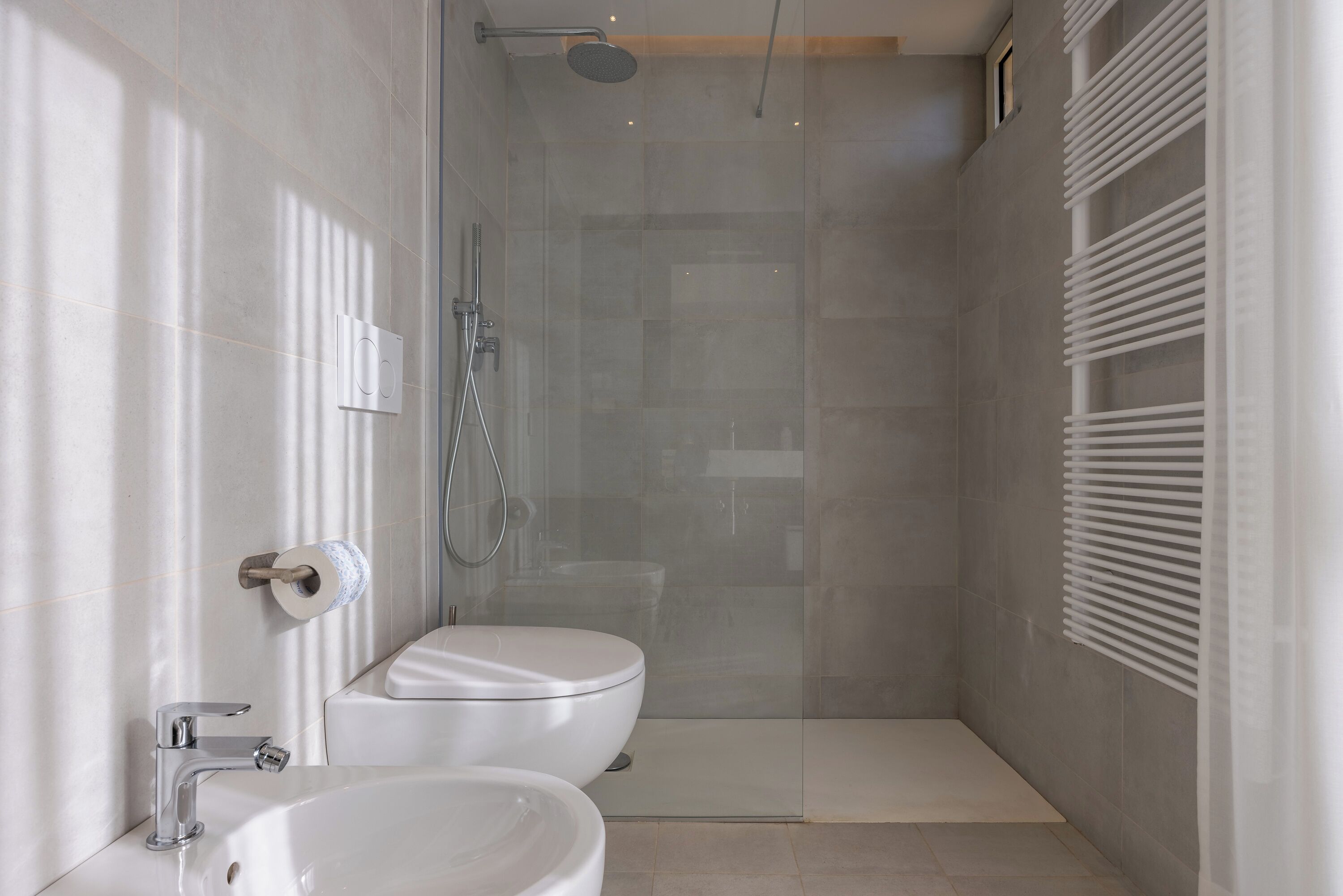 Un baño moderno con ducha envuelta en vidrio, inodoro y lavamanos.
