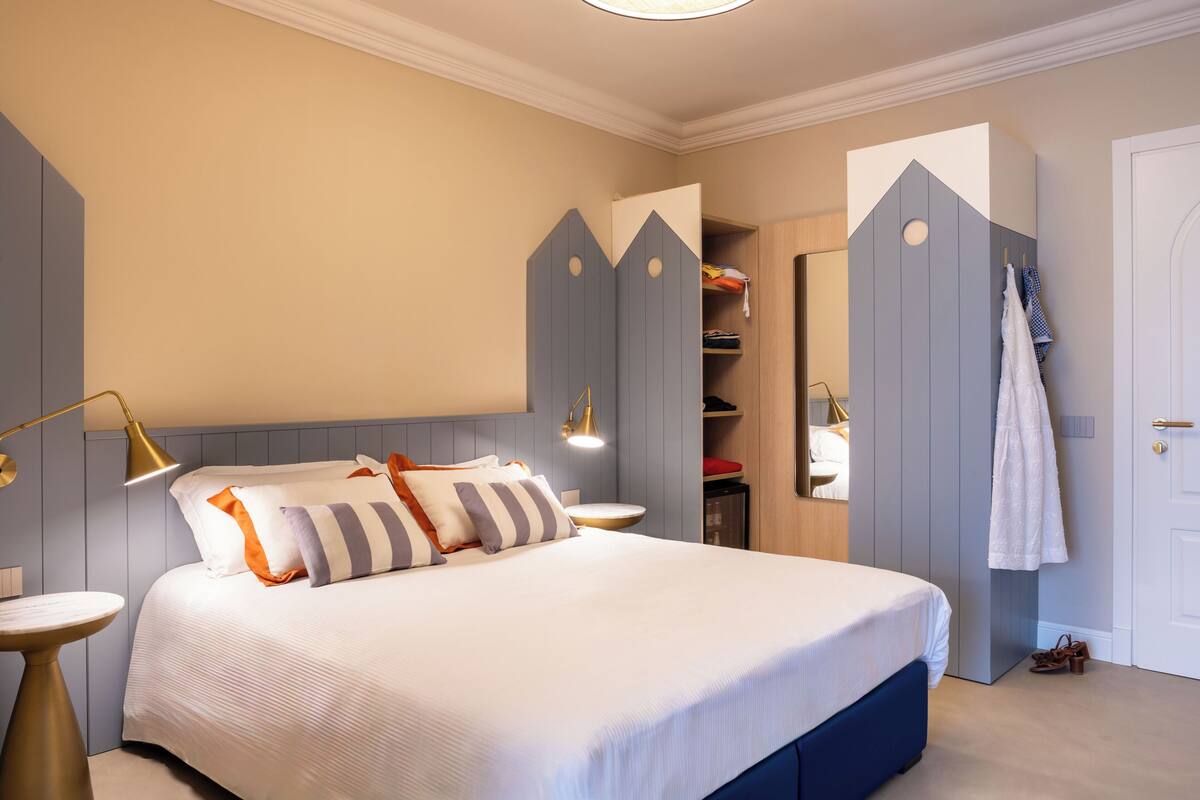 A neatly arranged bedroom with a bed, bedside table, and a wardrobe with a unique geometric design.