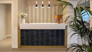 A modern bathroom with a white sink, black tiled backsplash, and three pendant lights.