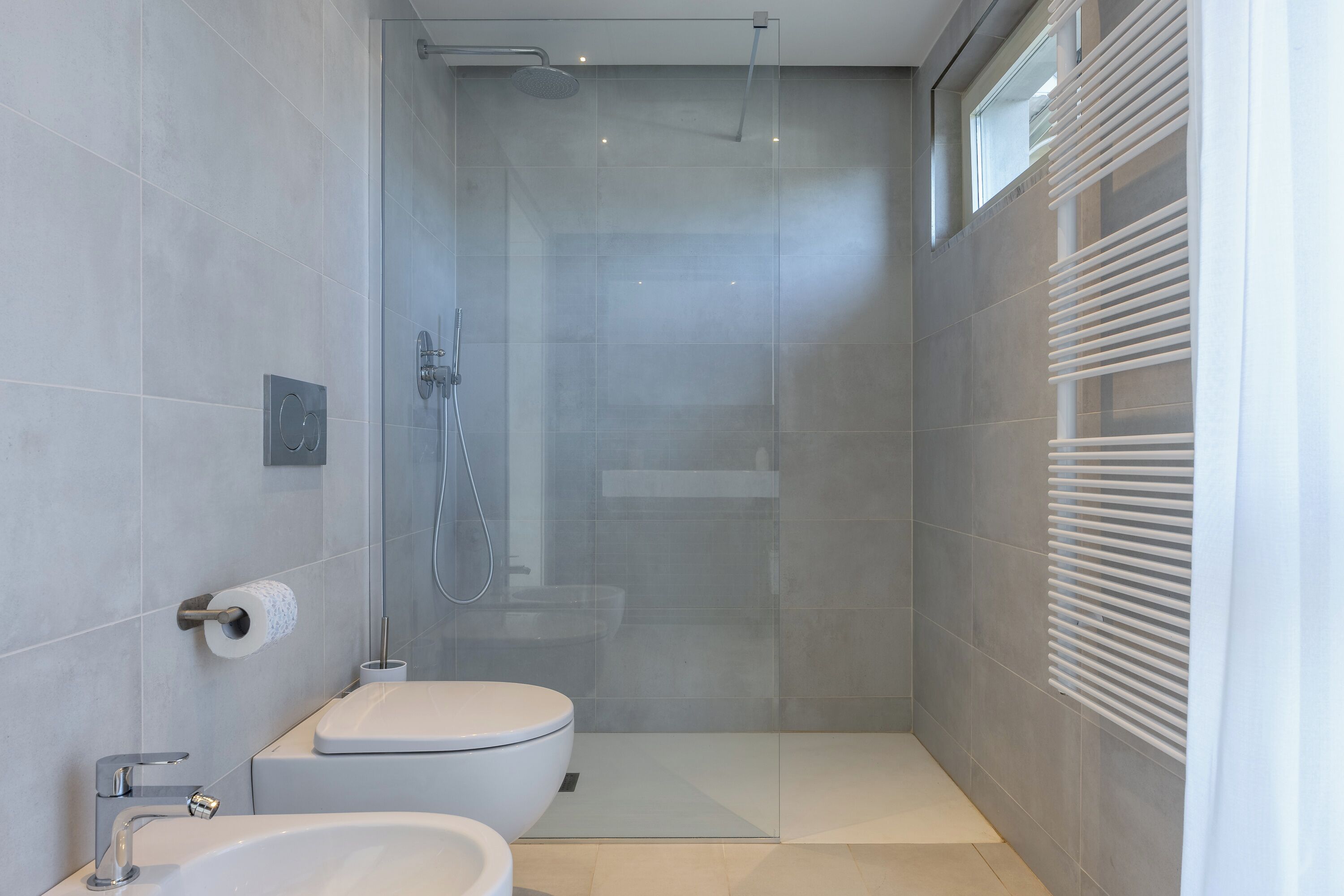 A modern bathroom with a glass-enclosed shower, a toilet, and a sink.