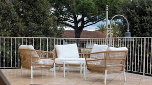 A balcony with wicker furniture, a white table, and a metal railing.