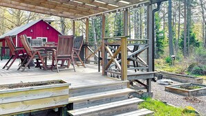A wooden deck with outdoor furniture, a red barn, and a forested backdrop. - 4 Star Holiday Home in Morlunda (Mörlunda)