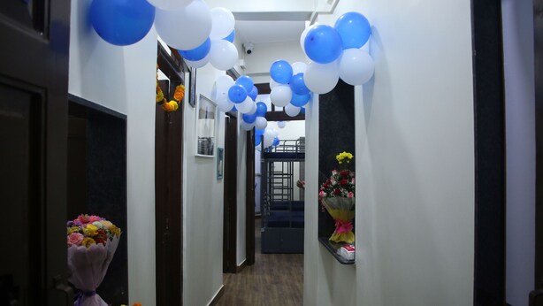 A hallway with blue and white balloons, a bouquet of flowers, and a staircase in the background. - Fostel The Fort Hostel (Mumbai)