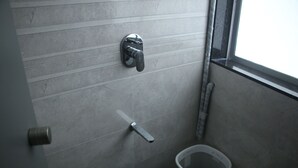 A bathroom with a toilet, a hand dryer, and a trash bin. - Fostel The Fort Hostel (Mumbai)