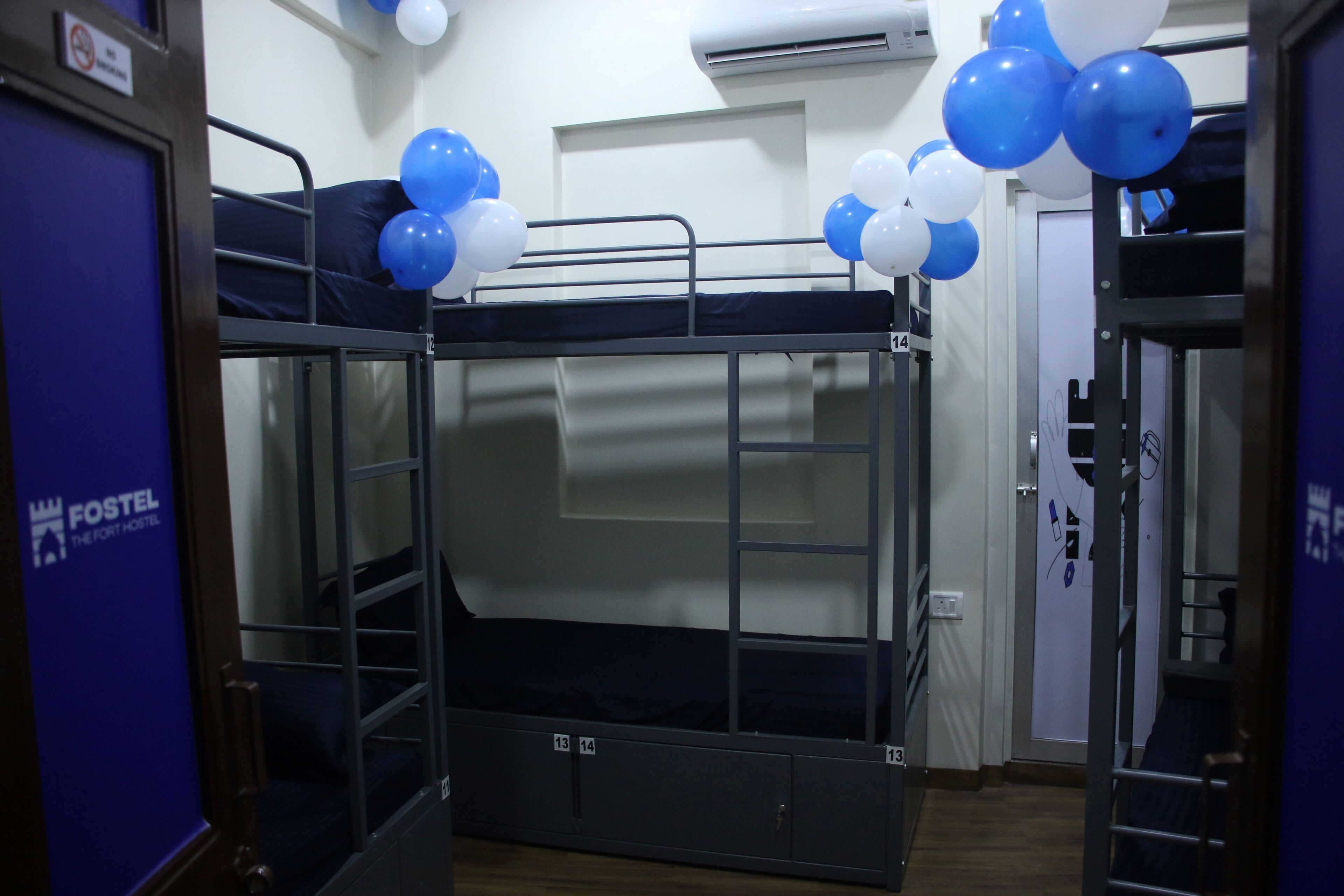 A bunk bed room with bunk numbers 13 and 14, a door with a 'No Smoking' sign, and balloons on the ceiling.
