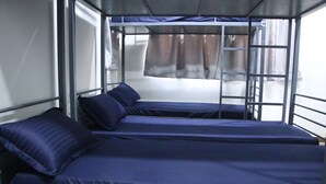 A bunk bed room with two beds, a ladder, and a window with curtains. - Fostel The Fort Hostel (Mumbai)
