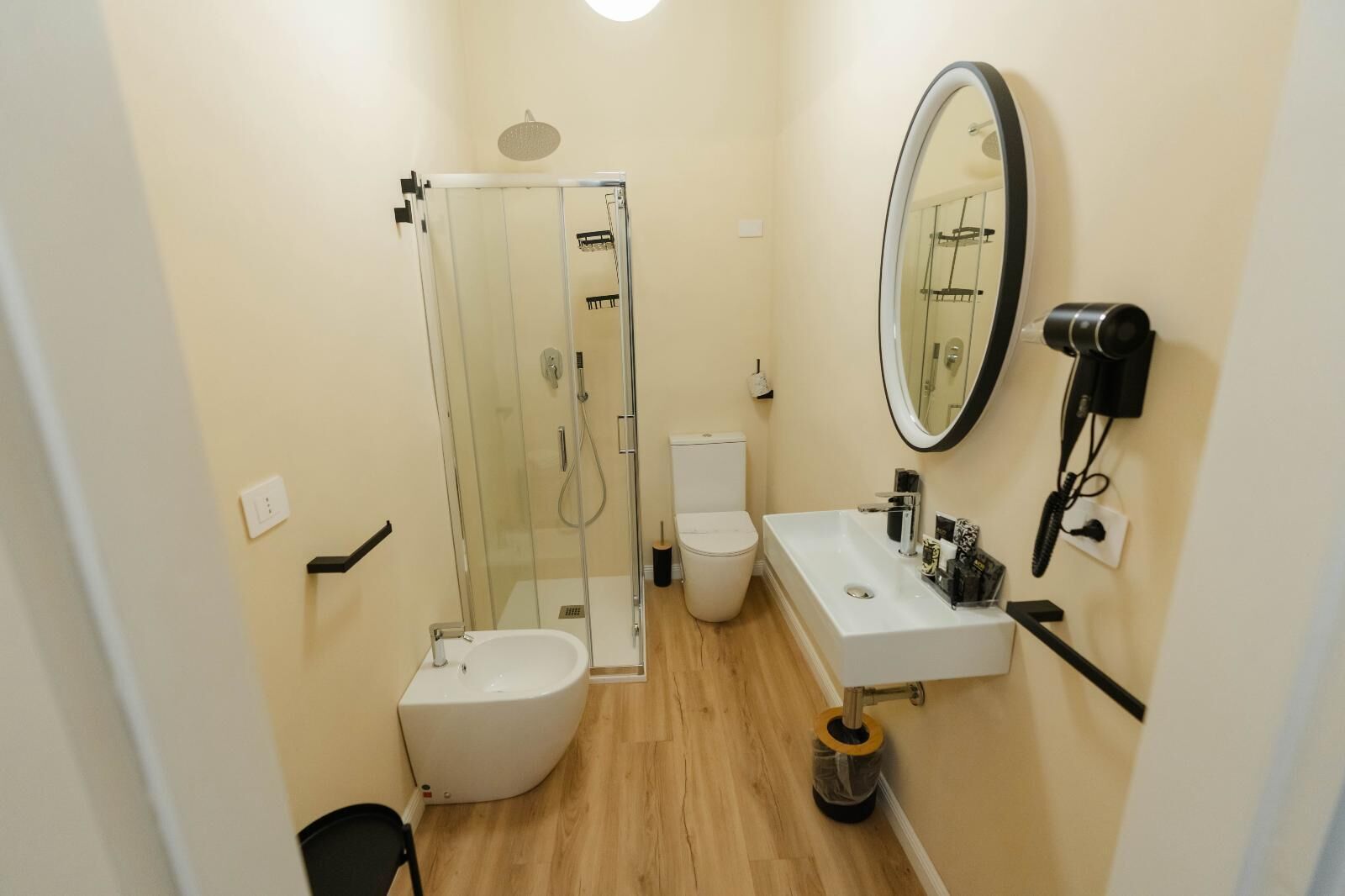 Ein kleines Badezimmer mit einer Duschkabine, einer weißen Toilette und einem Waschbecken mit Spiegel.