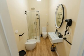 Un baño pequeño con ducha de vidrio, inodoro blanco y lavamanos con espejo.
