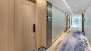 Een moderne hotelgang met houten deuren, een digitaal scherm en een vloerbedekking.