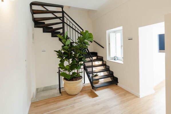 Un escalier avec des rampes noires, une plante en pot et une fenêtre donnant sur un beau paysage.