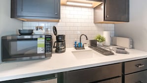 Una cocina moderna con armarios oscuros, un microondas, una cafetera y un tostador.