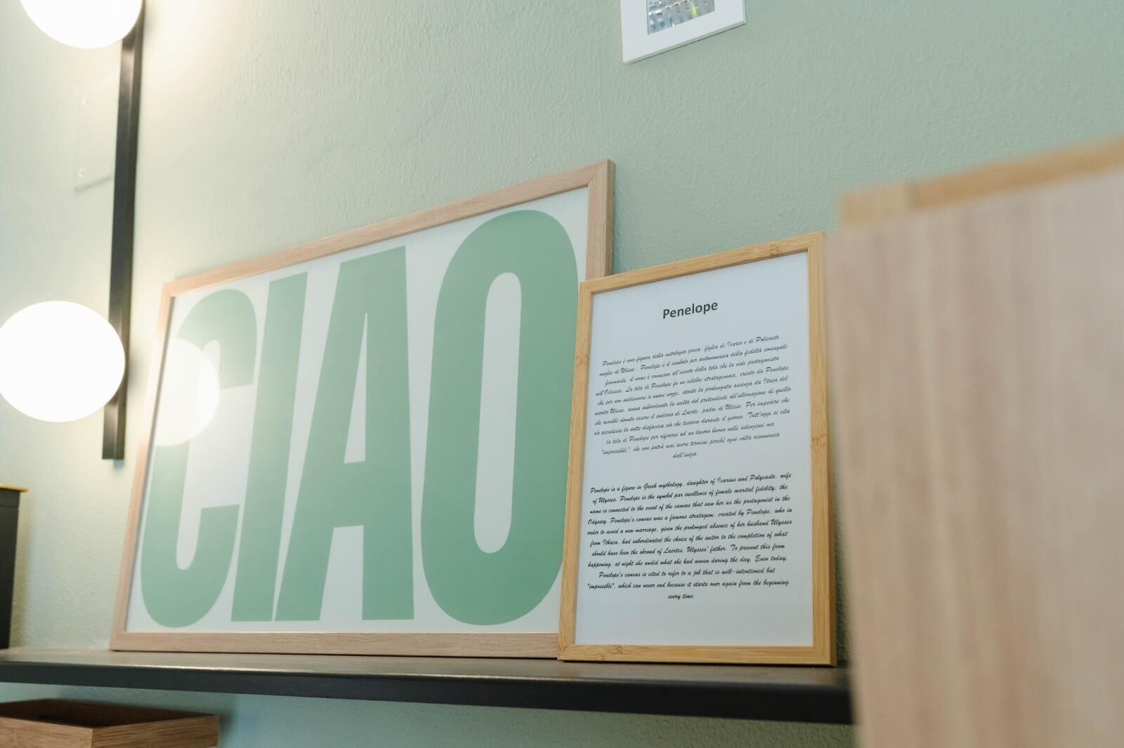 Et indrammet skilt med ordet "CIAO" og en mindre indrammet tekstplade med navnet "Penelope" på en væg.