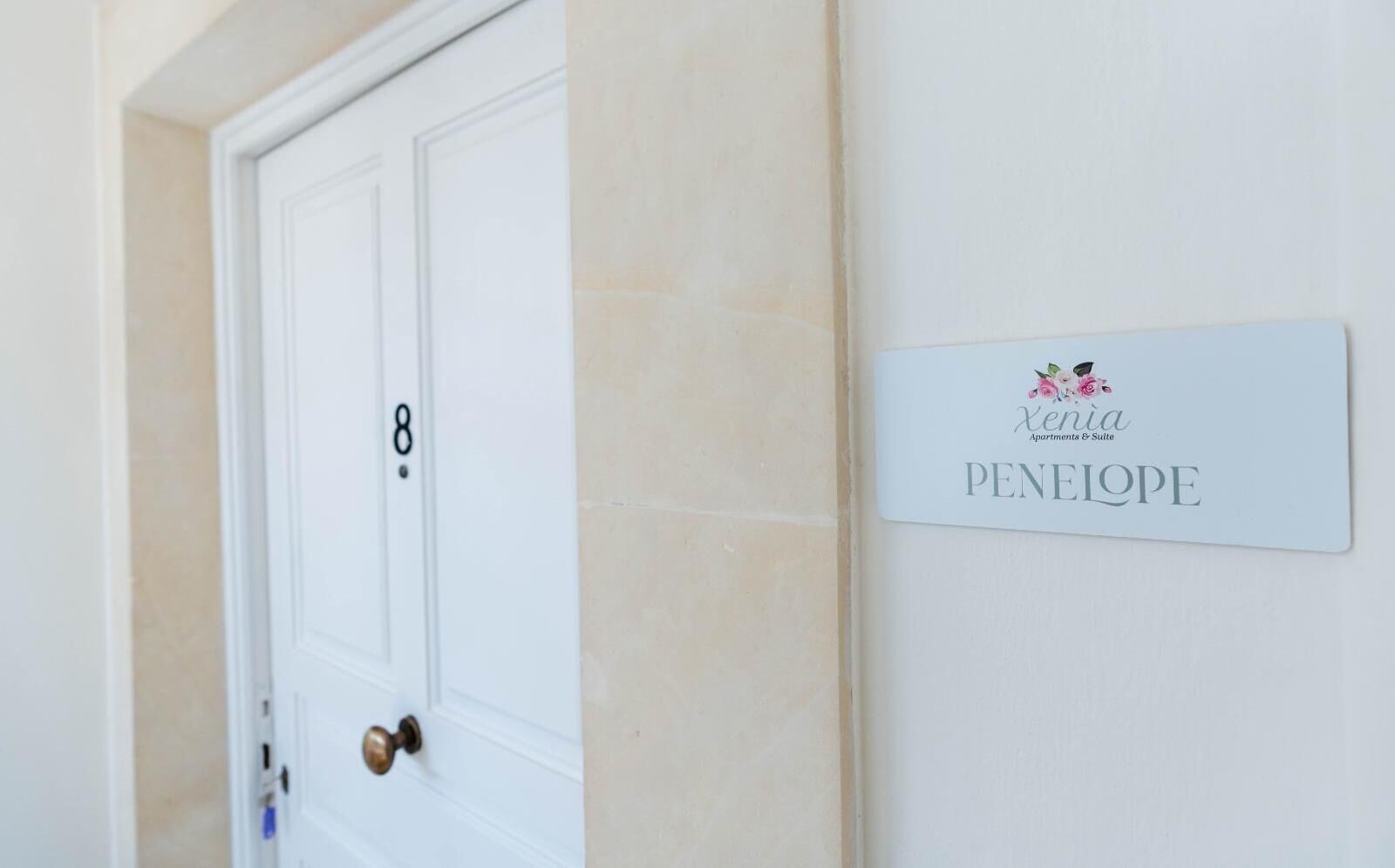 Una porta bianca con il numero 8 e una targa apposta sulla parete a destra.