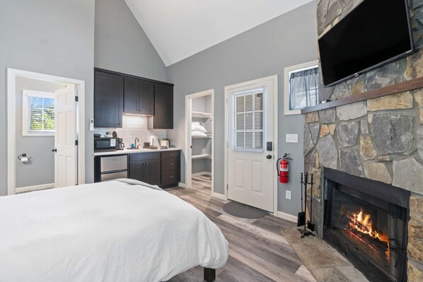 Une chambre à coucher avec un lit, une cheminée, une cuisine et une salle de bain.
