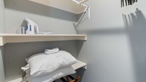 A bunk bed with a shelf above and a hanging rack to the right.