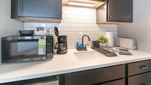 A modern kitchen with dark cabinets, a microwave, a coffee maker, and a toaster.