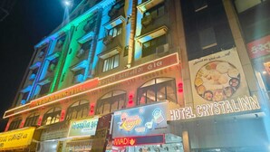 Ein mehrstöckiges Gebäude mit beleuchteten Schildern für ein Hotel und ein Teehaus.