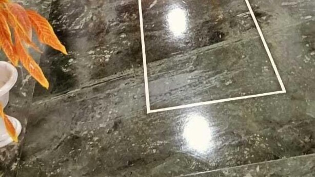 Ein glänzender Marmorfoyer mit geometrischem Bordendesign, das zu einer Tür am Ende führt.