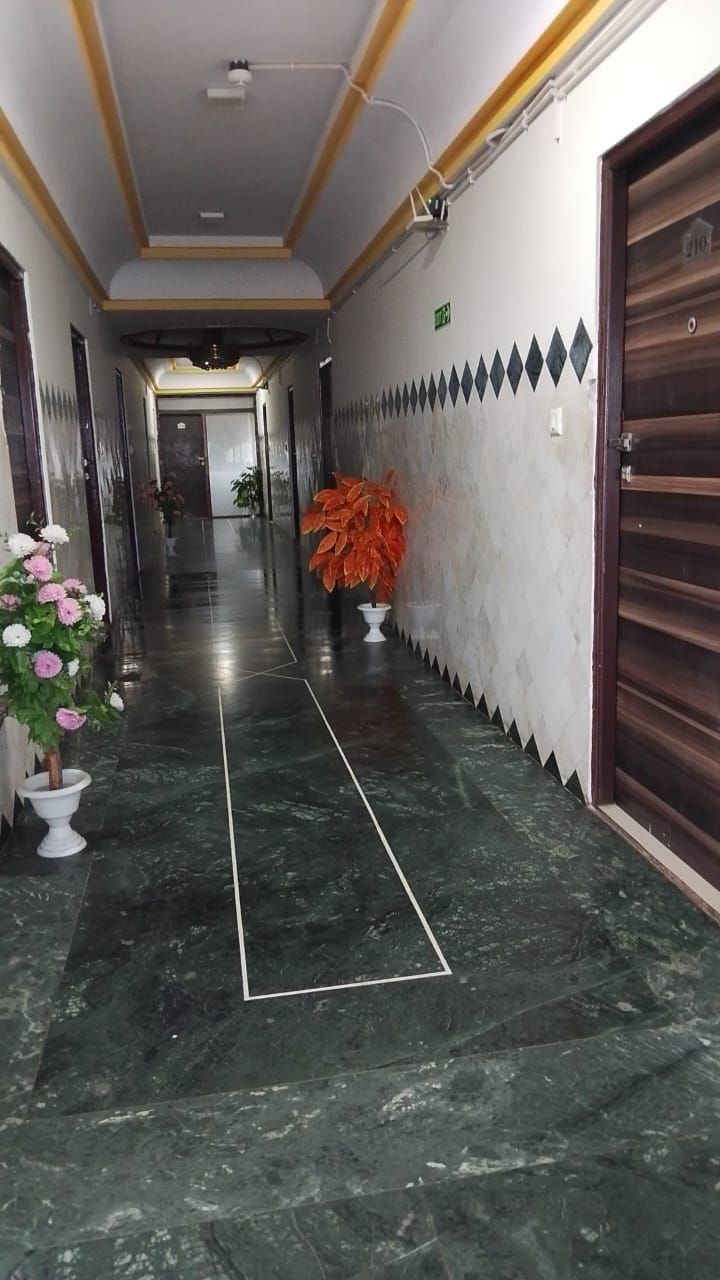 Un pasillo con suelo de mármol, plantas en macetas y una puerta con marco de madera.