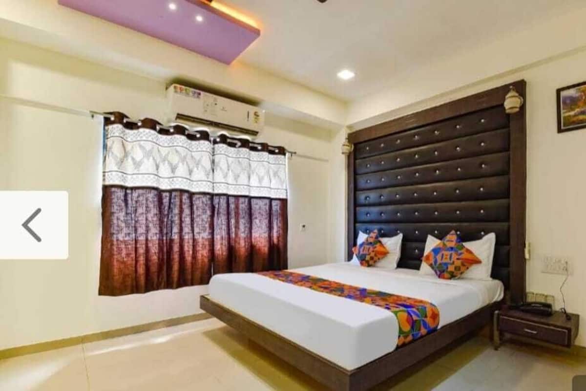 A bedroom with a large bed, a headboard, a nightstand, and a wall-mounted air conditioner.