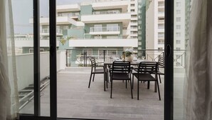 A balcony with a table set for dining, overlooking a residential area with multi-story buildings. - Enjoy easy access to Sliema Seafront and Tigne Point just on your doorstep (Tas-Sliema)
