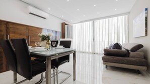 A modern dining area with a glass table, black chairs, and a potted plant. - Enjoy easy access to Sliema Seafront and Tigne Point just on your doorstep (Tas-Sliema)