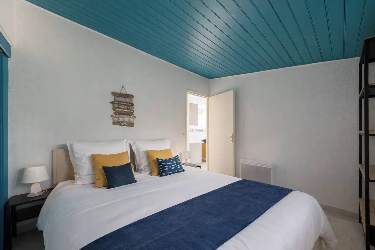 Ein Schlafzimmer mit einem Bett, Nachttischen, einer blauen Decke und einem an der Wand befestigten Schild.