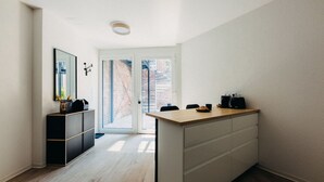 A modern kitchen with a central island, a black cabinet, and a large window. - Design & comfort | Stylish & cozy | Netflix (Düsseldorf)
