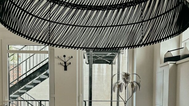 A modern living room with a sofa, a round table, and a decorative ceiling structure. - Industrial Loft | Smart TV | High-Speed WiFi (Düsseldorf)