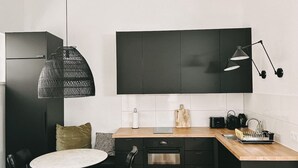 A modern kitchen with black cabinets, a wooden countertop, a round dining table, and a black pendant light. - Industrial Loft | Smart TV | High-Speed WiFi (Düsseldorf)