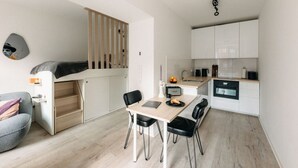 A compact living space with a kitchenette, a dining area, and a convertible bed.