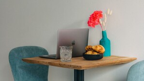 A laptop on a wooden table, a glass of water, and a bowl of croissants. - Central Stay | Design Apartment | Balcony & WiFi (Düsseldorf)