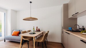 A modern kitchen with a dining area, featuring a wooden table, chairs, and a hanging light fixture. - Boho Meets Modern - The Perfect City Escape (Düsseldorf)