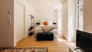 A modern bedroom with a bed, bedside tables, a TV, and a window. - Boho Meets Modern - The Perfect City Escape (Düsseldorf)