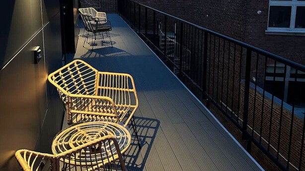 Une terrasse sur le toit, avec des fauteuils en osier et une vue sur le paysage urbain.