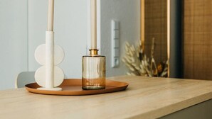 Une table en bois, une bouteille en verre et deux chandeliers blancs.