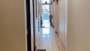 A hotel corridor with a tiled floor, recessed ceiling lights, and a door on the left. - R K Lodge And Palace  (Ayodhya)