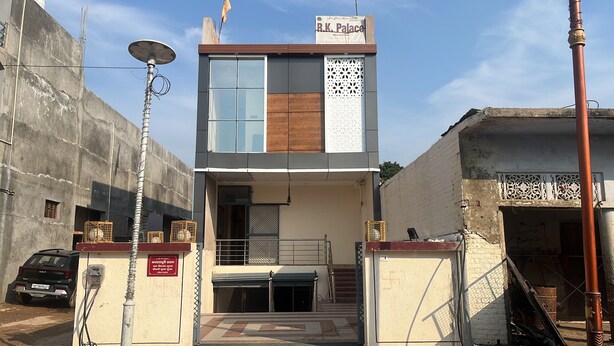 A two-story building with a flat roof, a signboard, and a gated entrance. - R K Lodge And Palace  (Ayodhya)