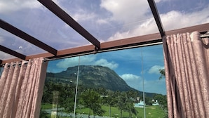 Ein Zimmer mit großem Fenster und Blick auf Berg und grüne Landschaft.